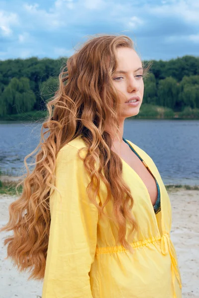 Portrait de jeune femme séduisante aux cheveux longs en tenue jaune sur la plage de rivière — Photo