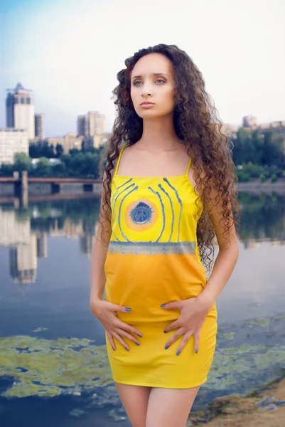Young women in yellow outfit on river and city background — Stock Photo, Image