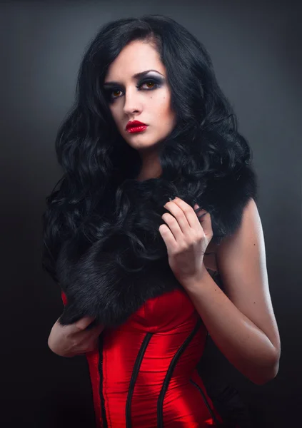 Sexy Brünette in rotem Korsettpelz und langen Haaren im Studio — Stockfoto