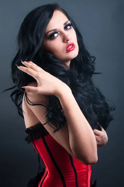 Morena sexy em pele de espartilho vermelho e cabelo longo no estúdio — Fotografia de Stock