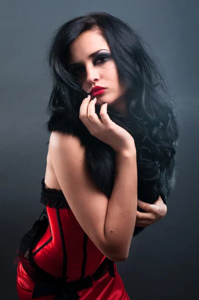 Σέξι μελαχρινή σε κόκκινο κορσέ γούνα και μακριά μαλλιά σε στούντιο — Φωτογραφία Αρχείου