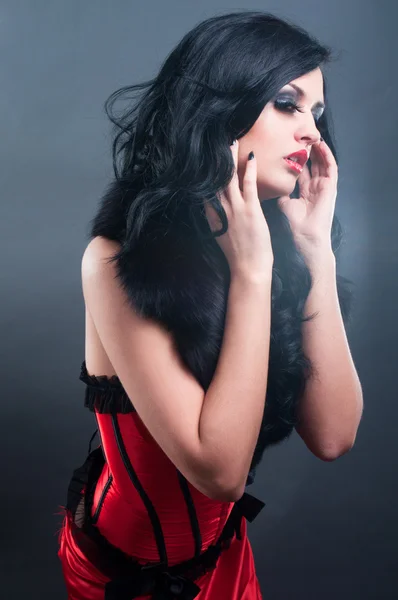 Sexy Brünette in rotem Korsettpelz und langen Haaren im Studio — Stockfoto