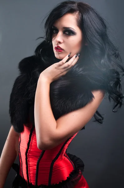 Σέξι μελαχρινή σε κόκκινο κορσέ γούνα και μακριά μαλλιά σε στούντιο — Φωτογραφία Αρχείου