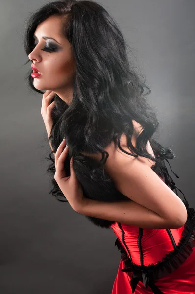Bruna sexy in pelliccia di corsetto rosso e capelli lunghi in studio — Foto Stock