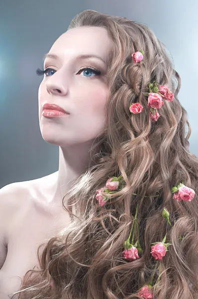Portrét krása s červenými růžemi ve vlasech — Stock fotografie