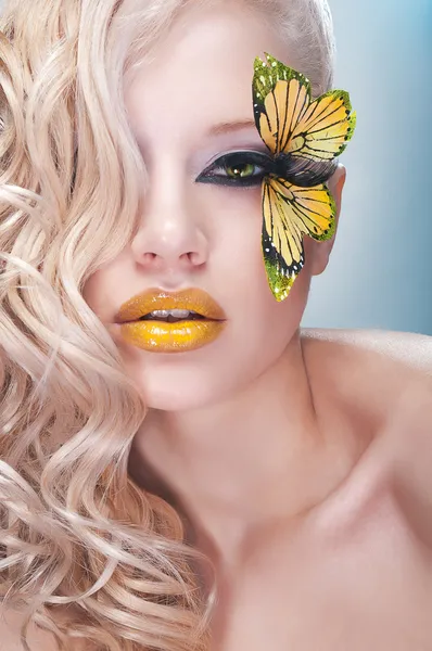 Блондинка кучерява жінка з жовтим метеликом на віях — стокове фото