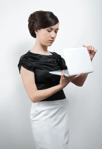 Молодая женщина в черно-белом костюме с ноутбуком — стоковое фото