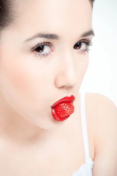 Studio portrait of young woman with strawberry in a mouth isolat — Stock Photo, Image