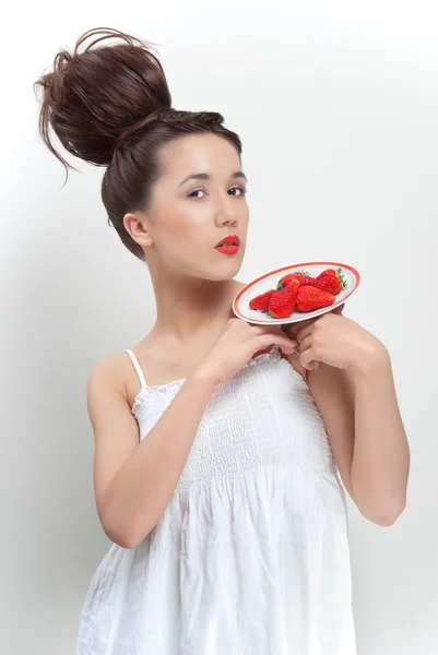 Mladá krásná žena v bílých šatech hospodářství talířek s jahodou — Stock fotografie