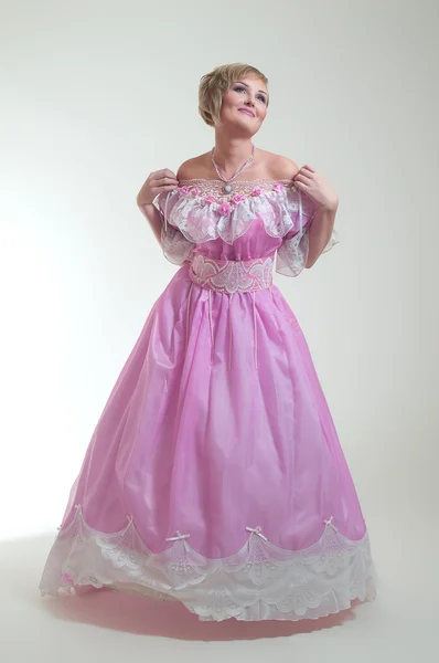Blonde vrouw in mooie lange roze jurk — Stockfoto