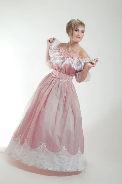 Blond kvinna i vacker lång rosa klänning Stockbild