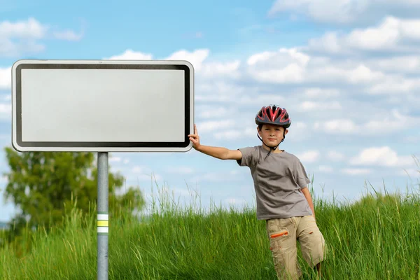 Boy cyclist leaning on blank sign — Stock Photo, Image