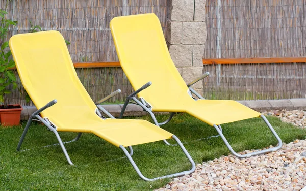 Twee lege gele ligstoelen op een tuin — Stockfoto
