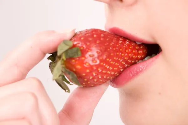 Primer plano de la mujer tomando un bocado de fresas frescas jugosas —  Fotos de Stock