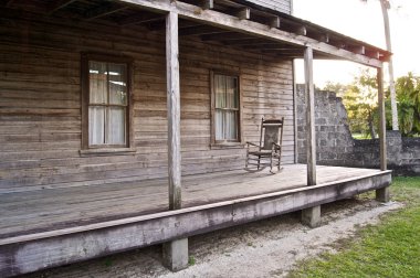 Old wooden home with rocking chair clipart