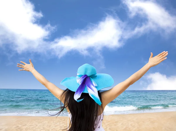 Молодая женщина поднимает руки на пляже — стоковое фото