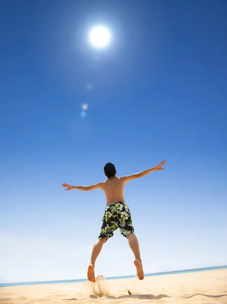 Счастливый молодой человек прыгает по пляжу — стоковое фото