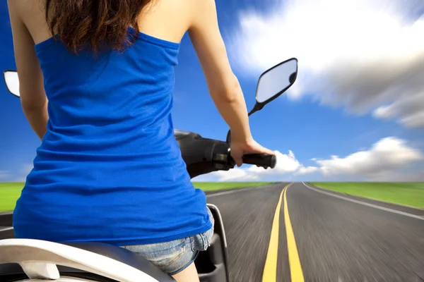 Slanke vrouw rijden scooter met hoge snelheid op de weg — Stockfoto