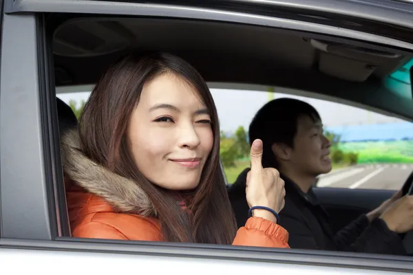 Gelukkige lachende paar rijden in de auto met duimen omhoog — Stockfoto