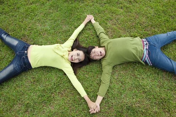 Happy asian couple lying on the grass — Stock Photo, Image