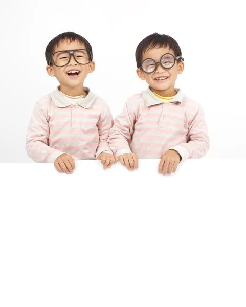 Duas crianças felizes atrás do quadro branco — Fotografia de Stock