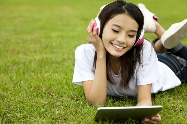 Счастливая девушка с планшетным компьютером на траве — стоковое фото