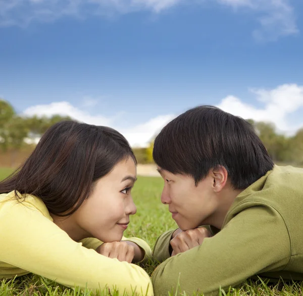 Feliz pareja asiática tumbada en la hierba con fondo de nube —  Fotos de Stock