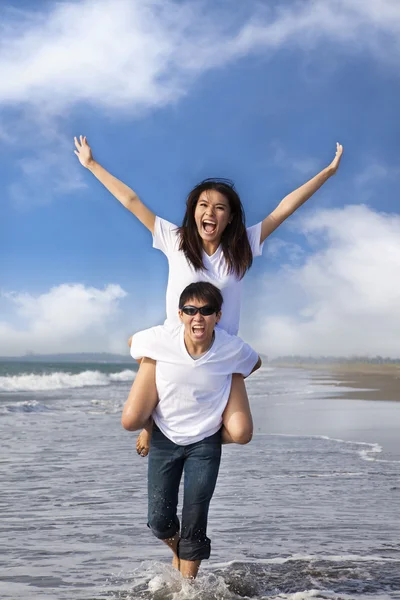 Casal feliz correndo na água na praia — Fotografia de Stock