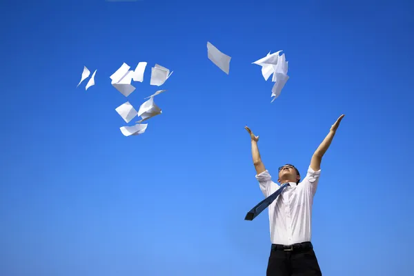Business man relaxing and throwing white papers to the blue sky — Stock Photo, Image