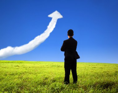 Business man stand on the field and watch growth graph cloud