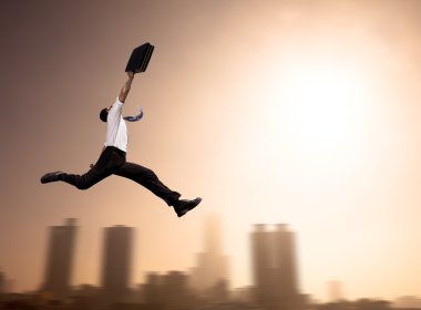 Excited Businessman running with cityscape background at morning clipart