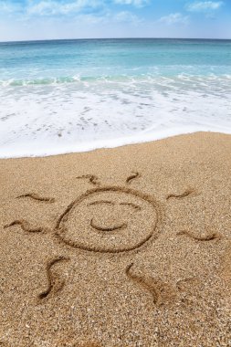 Drawing smiling sun symbol on the beach clipart