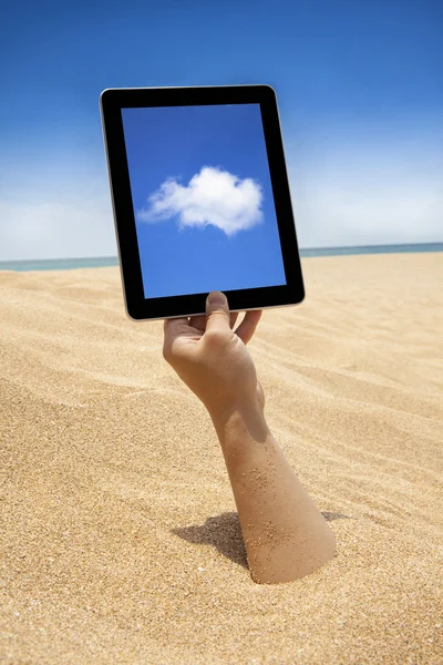 Mão segurando computador tela sensível ao toque na praia — Fotografia de Stock