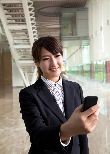 Junge Geschäftsfrau schaut Smartphone in der Hand — Stockfoto