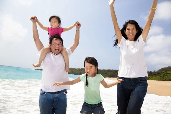 Счастливая азиатская семья прыгает по пляжу — стоковое фото
