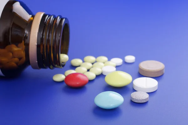 Rozlane tabletki i medycyna butelki. tabletki na niebieski deseń — Zdjęcie stockowe