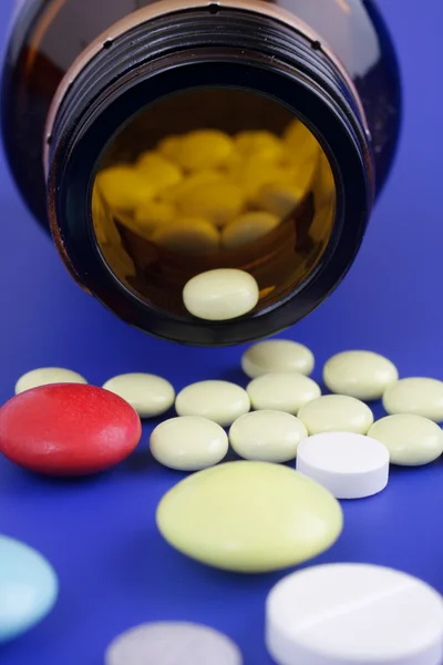 Spilled tablets and medicine bottle. Tablets on a blue backgroun — Stock Photo, Image