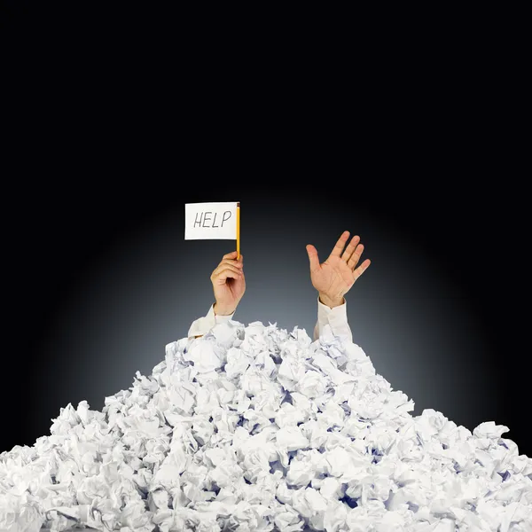 Persoon onder verfrommeld stapel papieren met hand met een help-si — Stockfoto