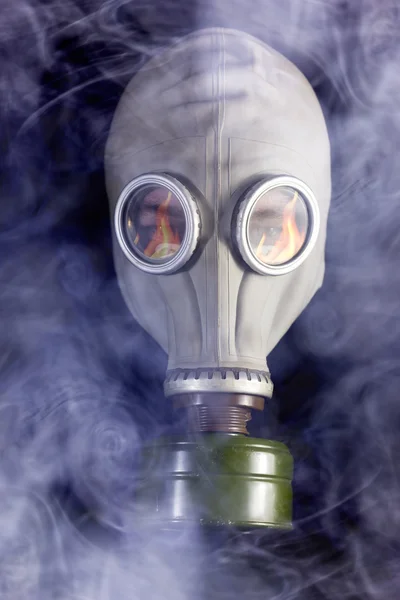 L'homme est dans un masque à gaz avec de la fumée autour et la réflexion du feu — Photo