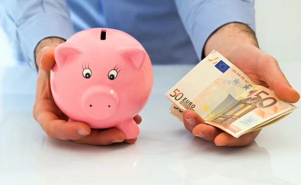 Mann mit Sparschwein und Stapel Euro-Banknoten. — Stockfoto