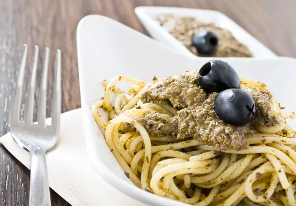 Spaghetti met zwarte olijven pesto. — Stockfoto