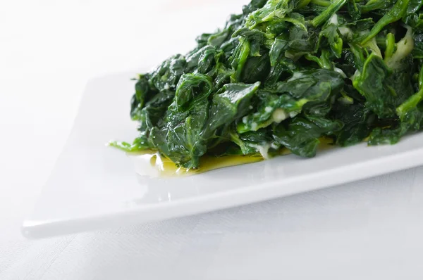 Gekochter Spinat auf weißem Teller. — Stockfoto