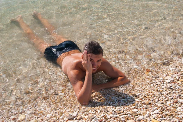 Beau jeune homme bronzé dans l'eau de mer — Photo