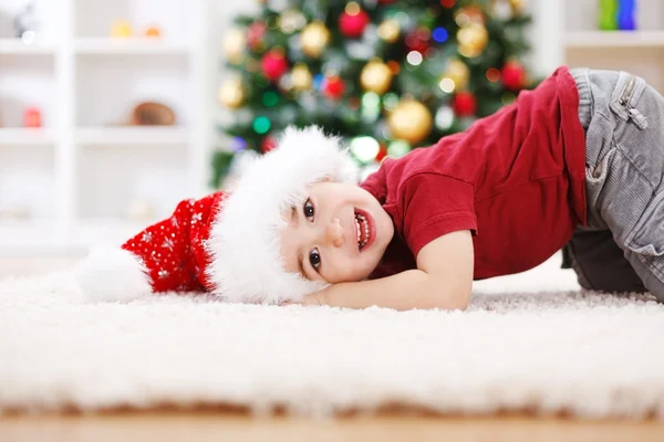 Lindo chico tendido frente al árbol de Navidad — Foto de Stock