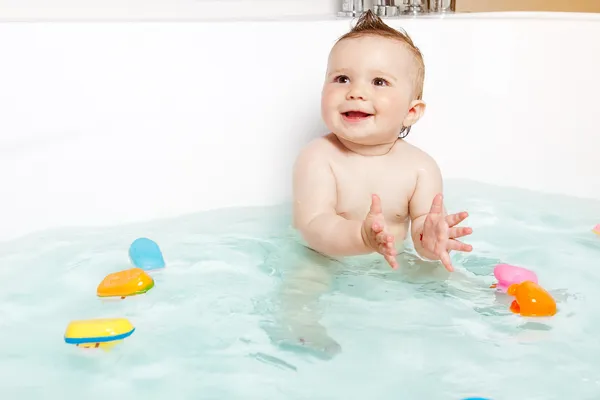 Lindo bebé aplaudiendo manos y sonriendo mientras toma un baño Fotos de stock