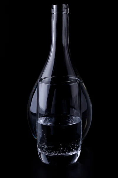 stock image Glass with a bottle of water on a black background