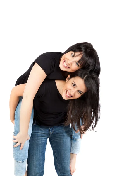 Dwóch młodych kobiet, uśmiechnięty i piggyback — Zdjęcie stockowe