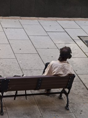 Beggar sitted on a bench clipart