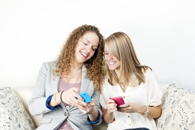 Two women using mobile devices clipart