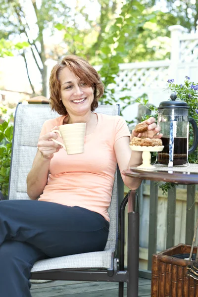 Mujer en el patio trasero con café y galletas — Foto de Stock